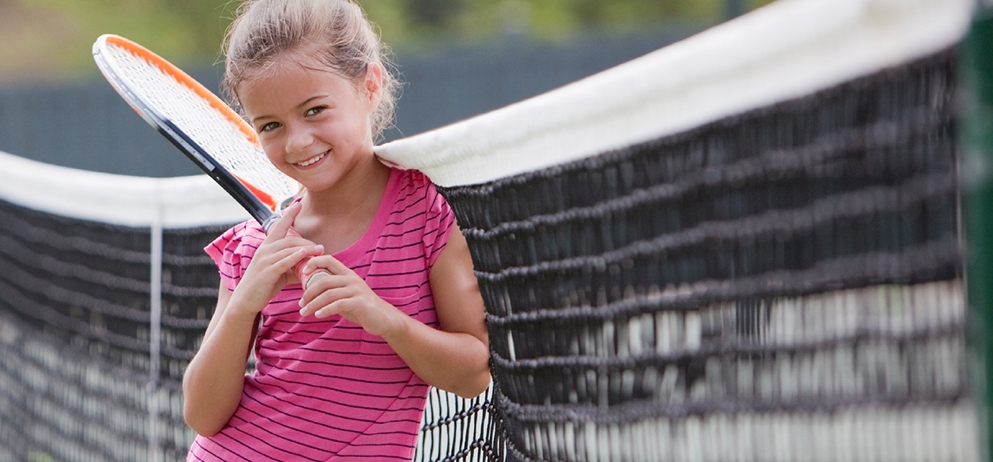 A child poses with a tennis racket