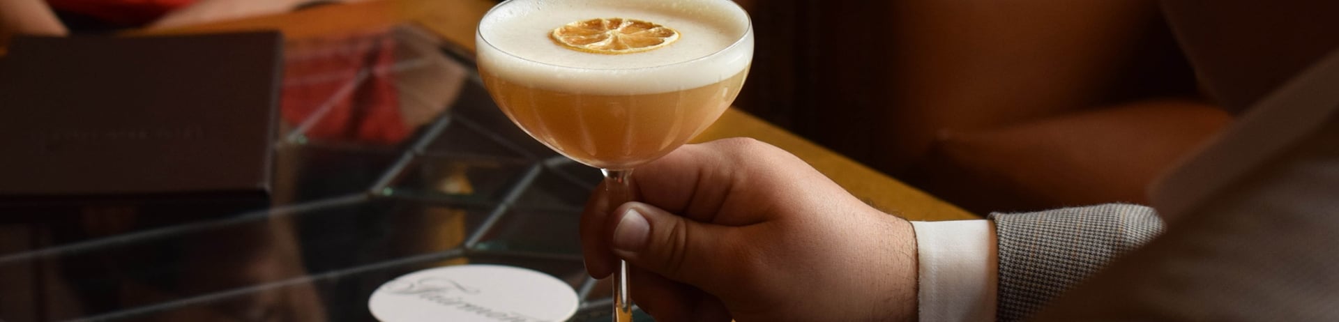 A man holds a glass of the Signature Baklava Sour