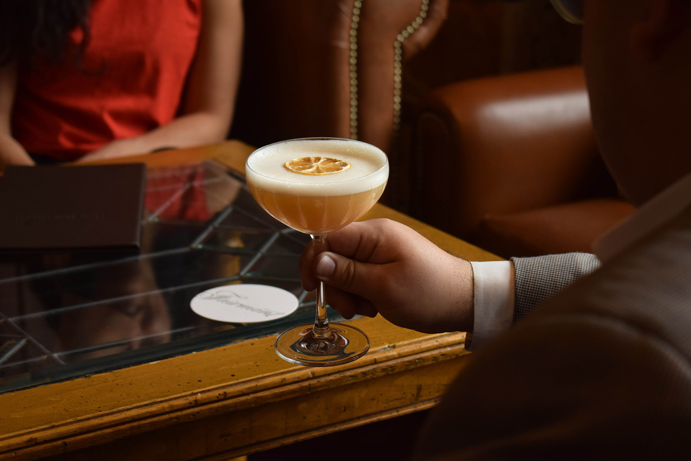 A man holds a glass of the Signature Baklava Sour