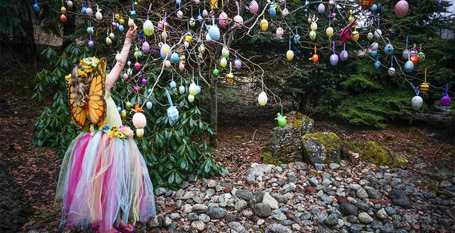 A butterfly princess reaches for an easter egg on a tree