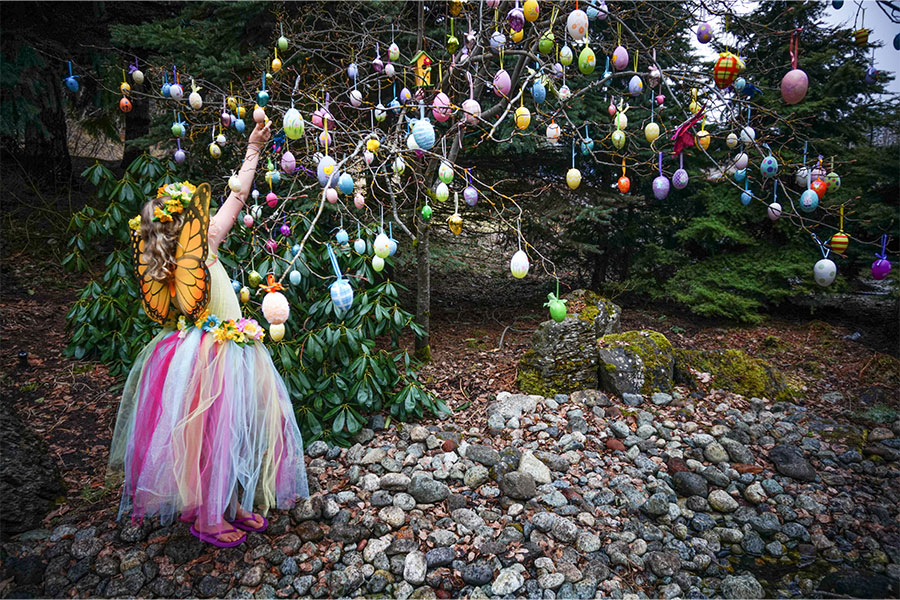 A butterfly princess reaches for an easter egg on a tree