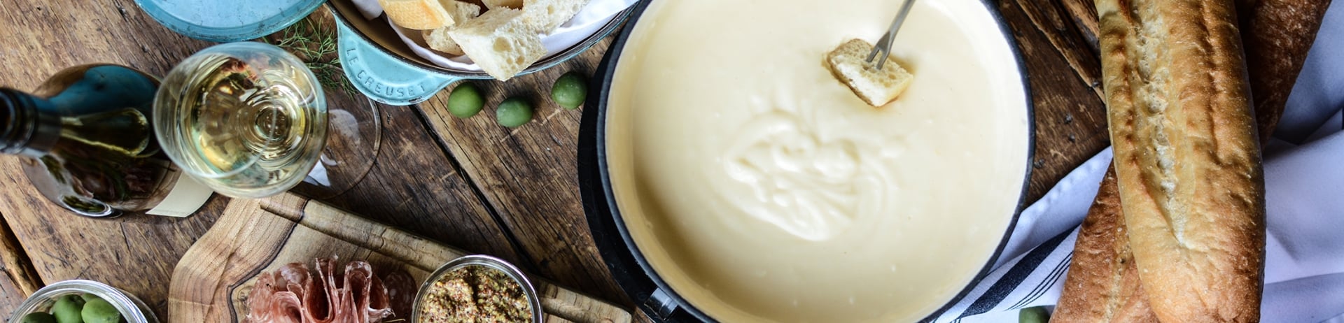 A spread of food on a table, including a pot of fondue