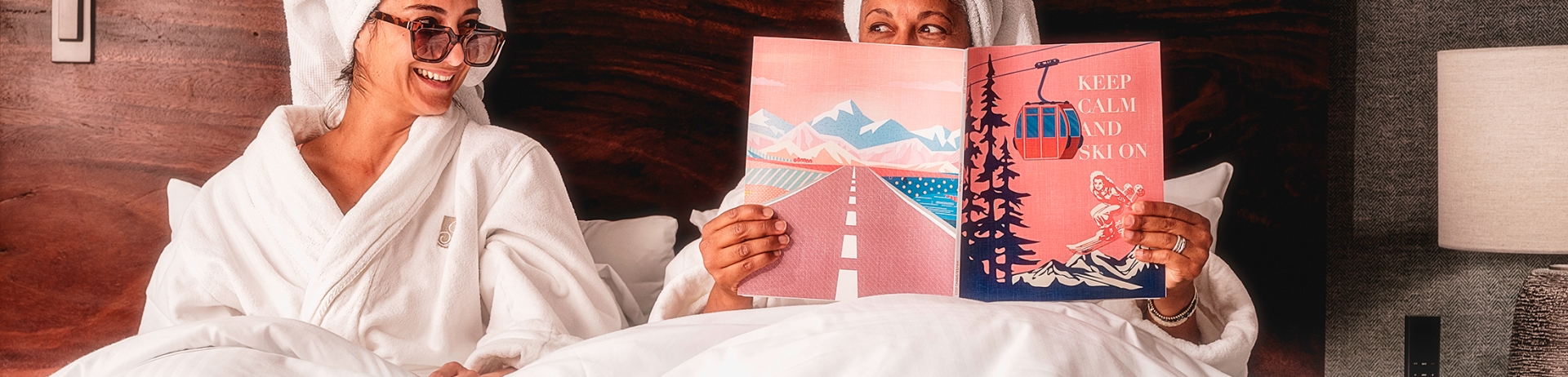 Two women sat up in bed with towels on their heads