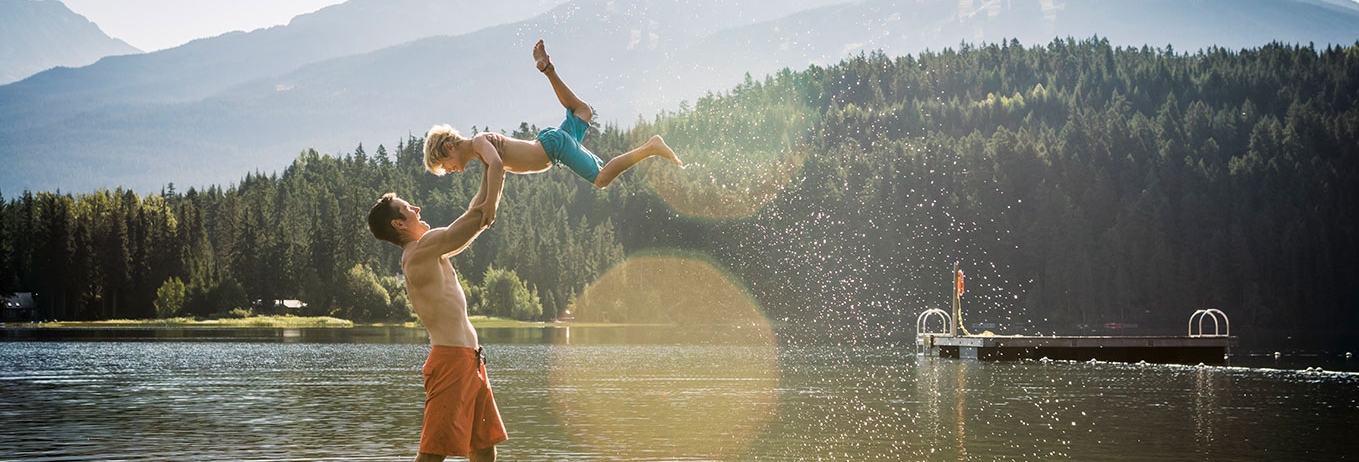 A man and his son laughing and playing in a lake