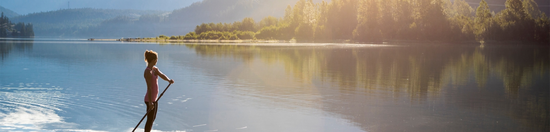 Female paddle boarder enjoying quiet morning on Green lake.