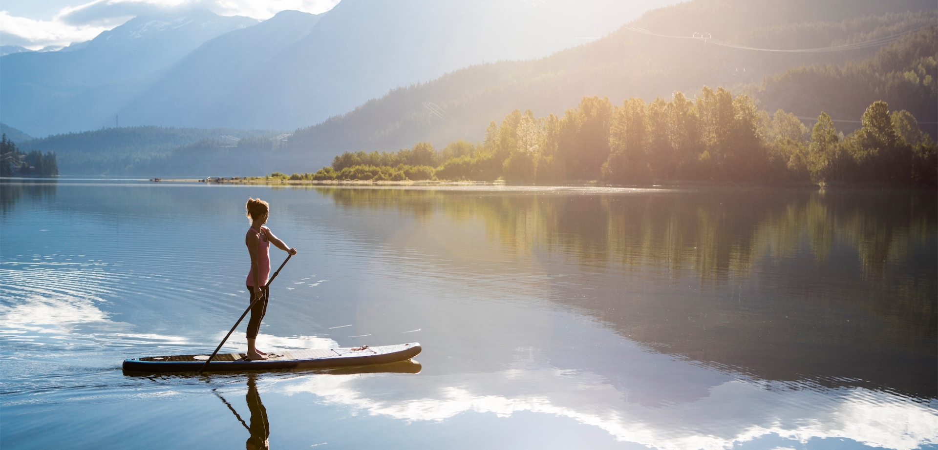 Female paddle boarder enjoying quiet morning on Green lake.