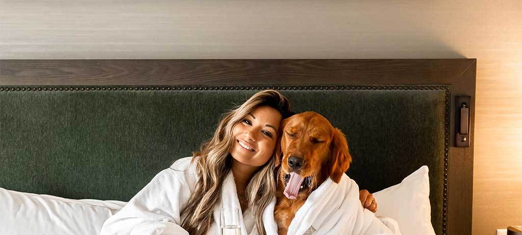 Woman with her dog in a hotel bed