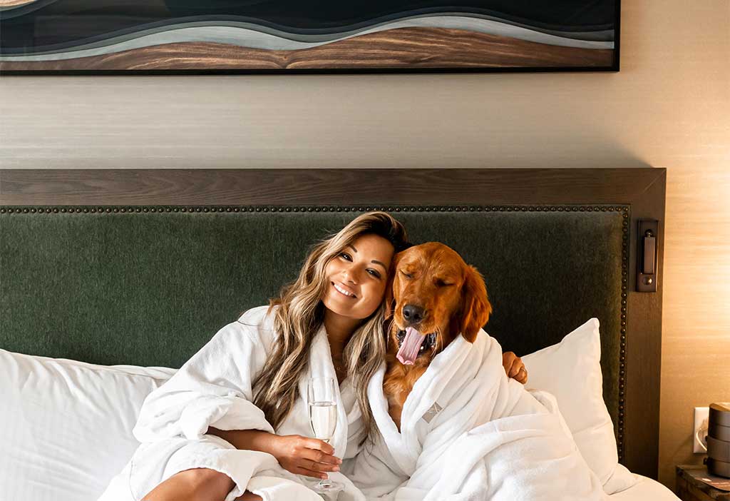 Woman with her dog in a hotel bed