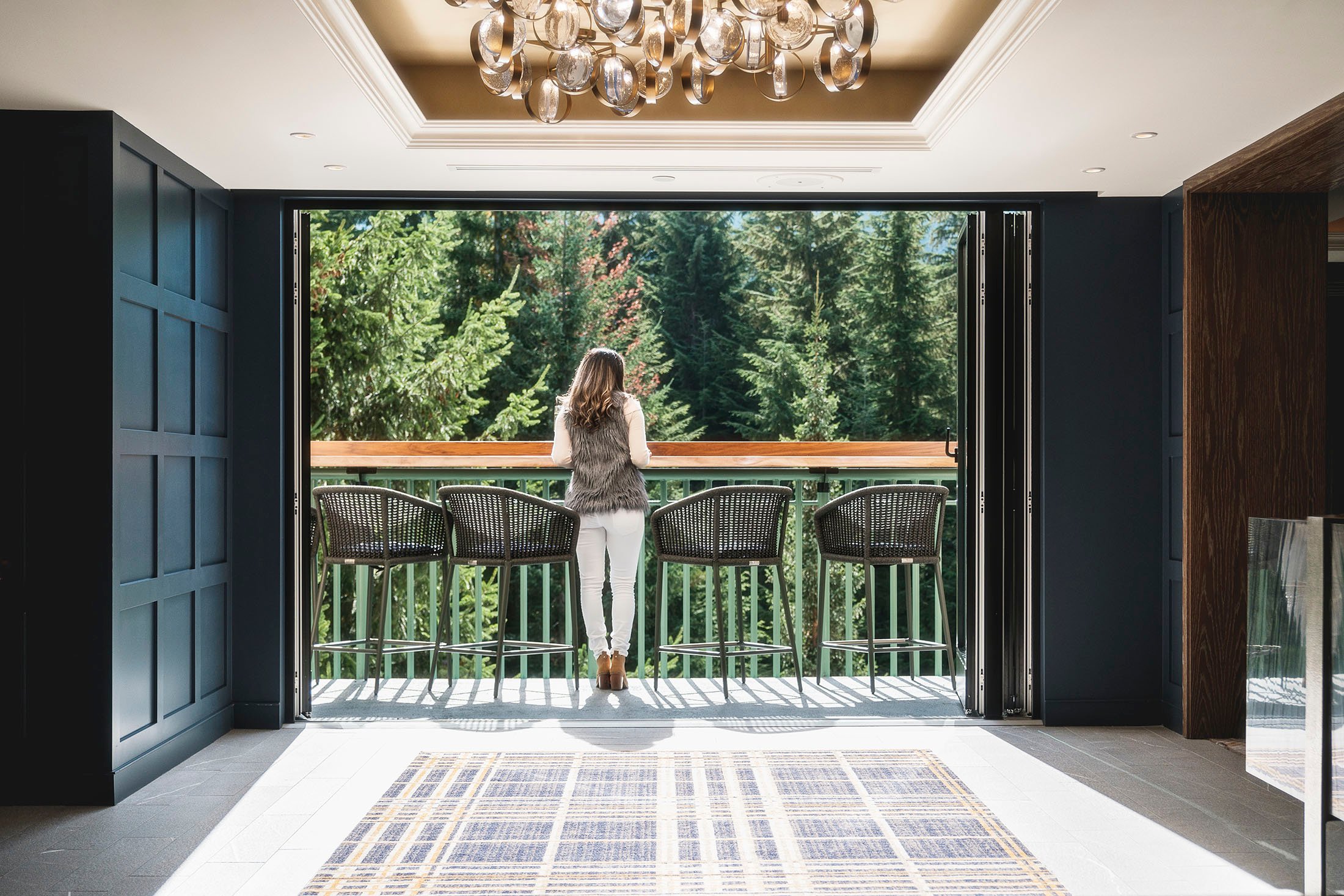 A woman stands on a patio overlooking trees