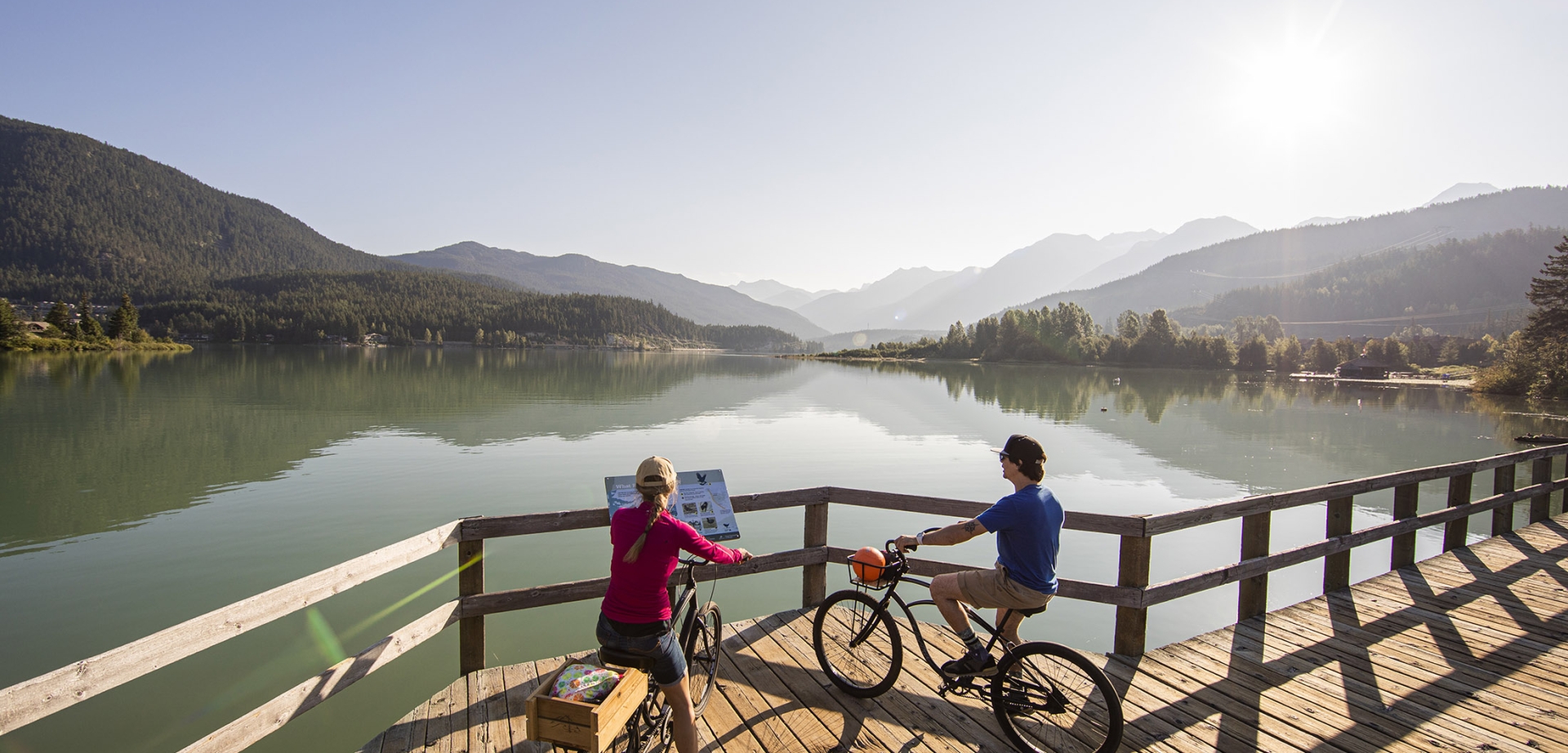 Two cyclists stop to look over the lake on a boardwalk