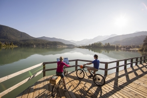 Two cyclists stop to look over the lake on a boardwalk