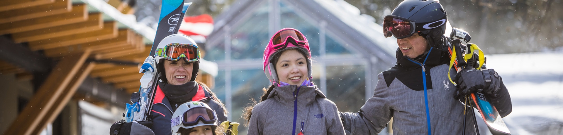 A family wearing snowsuits and carrying skis walking