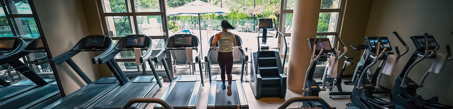 wide angle view of gym with treadmills and woman running