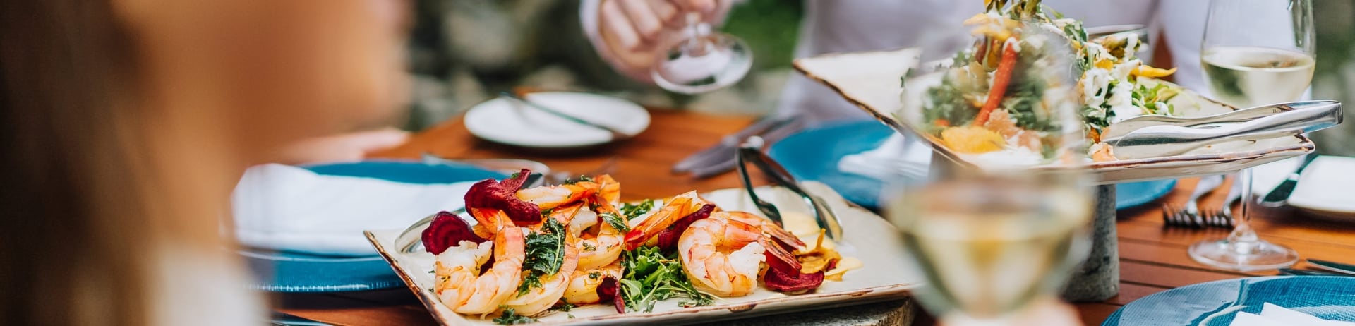 closeup of shrimp appetizer salad and couple drinking wine