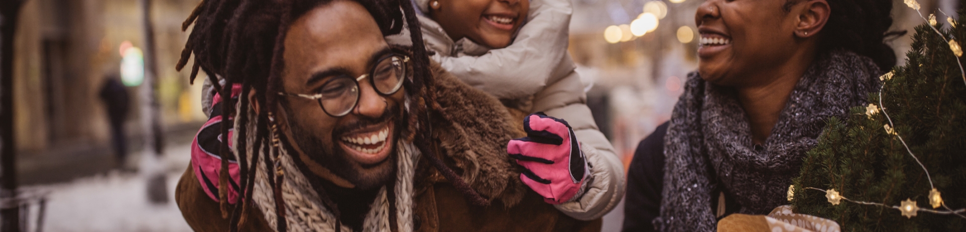 couple walking through snowy streets with daughter on back