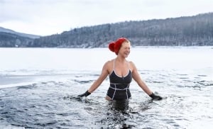 woman in bathing suit and red winter hat stands in a large body of water