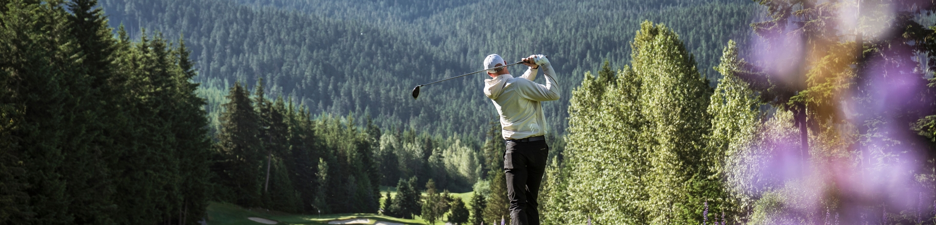 person playing golf with mountain in the background