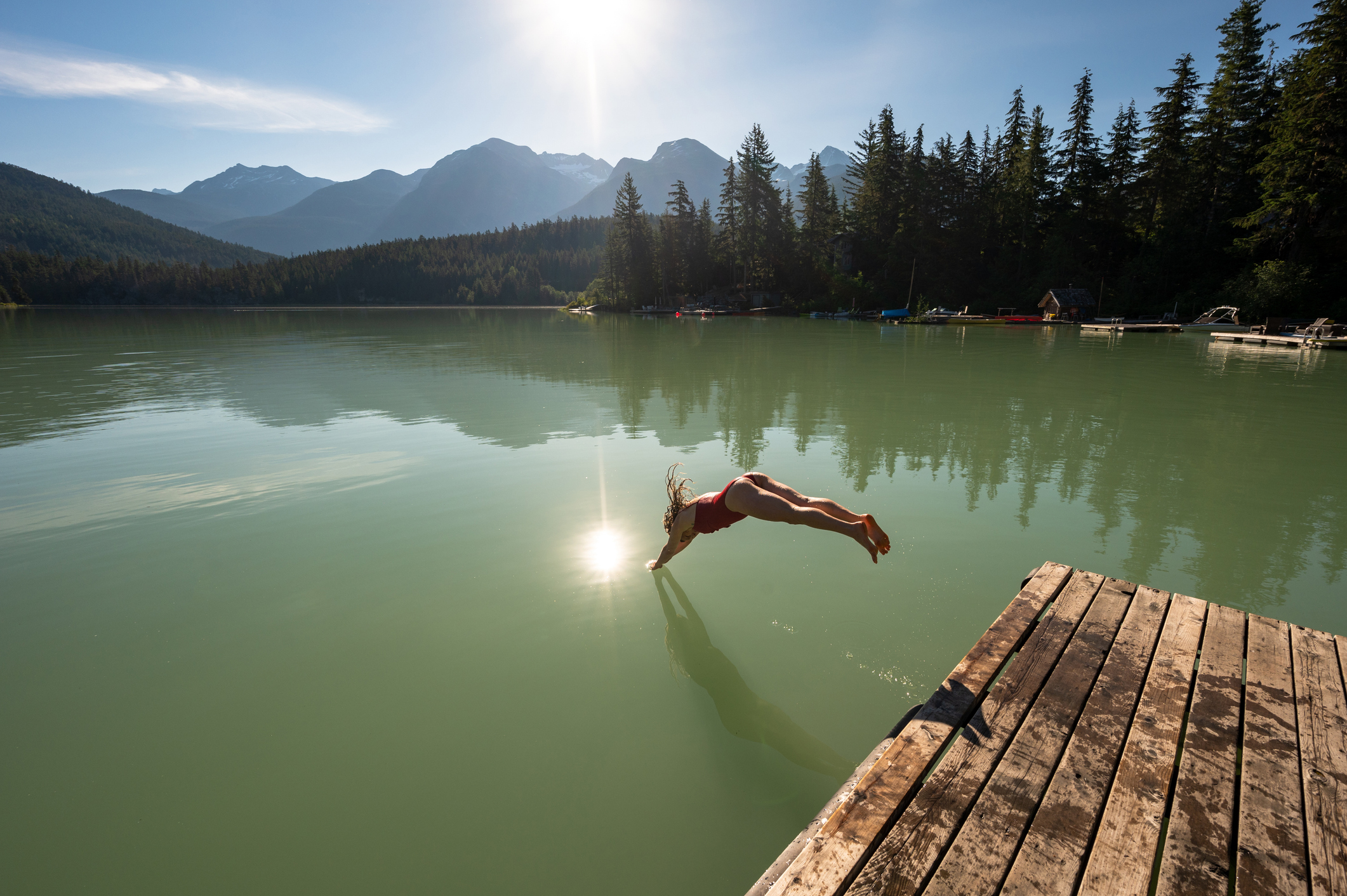Woman diving into green lake whistler spring mountain views