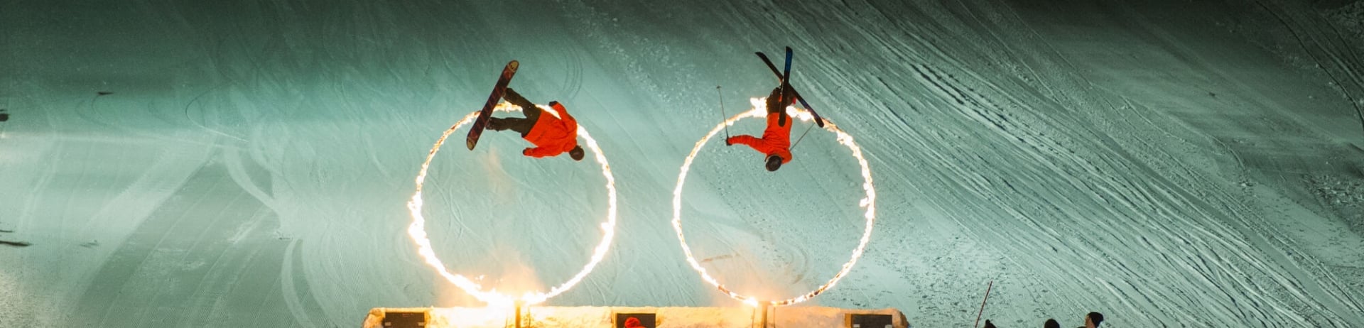 Skiers skiing through rings of fire.