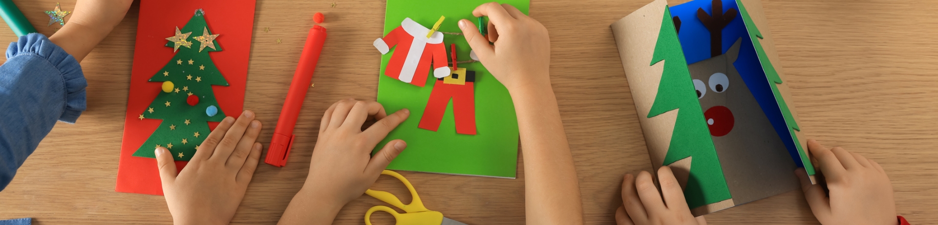 Little children making beautiful Christmas greeting cards at table, top view