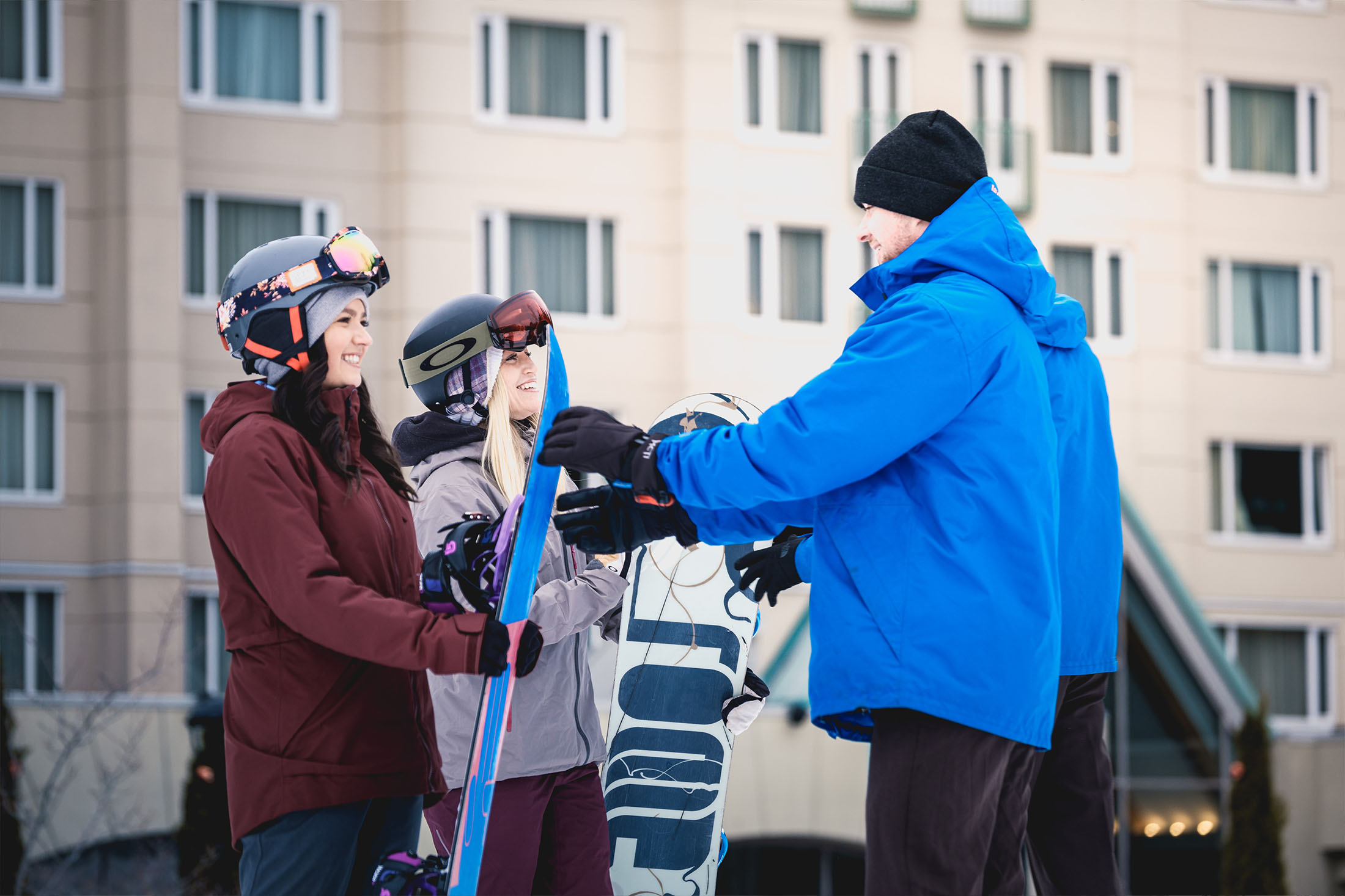 Snowboarders giving snowboard to ski valet.
