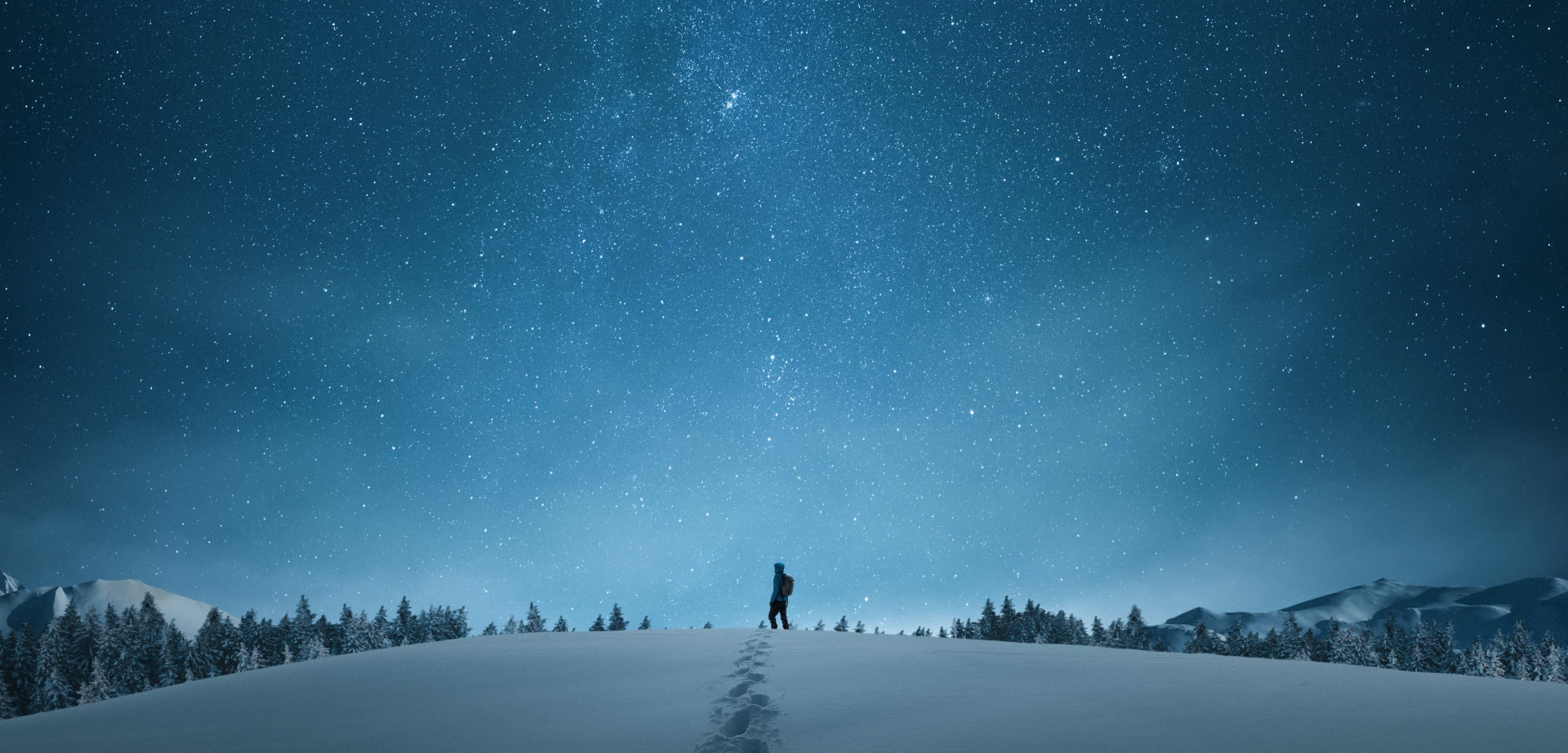 man knee deep in snow under a starry night sky