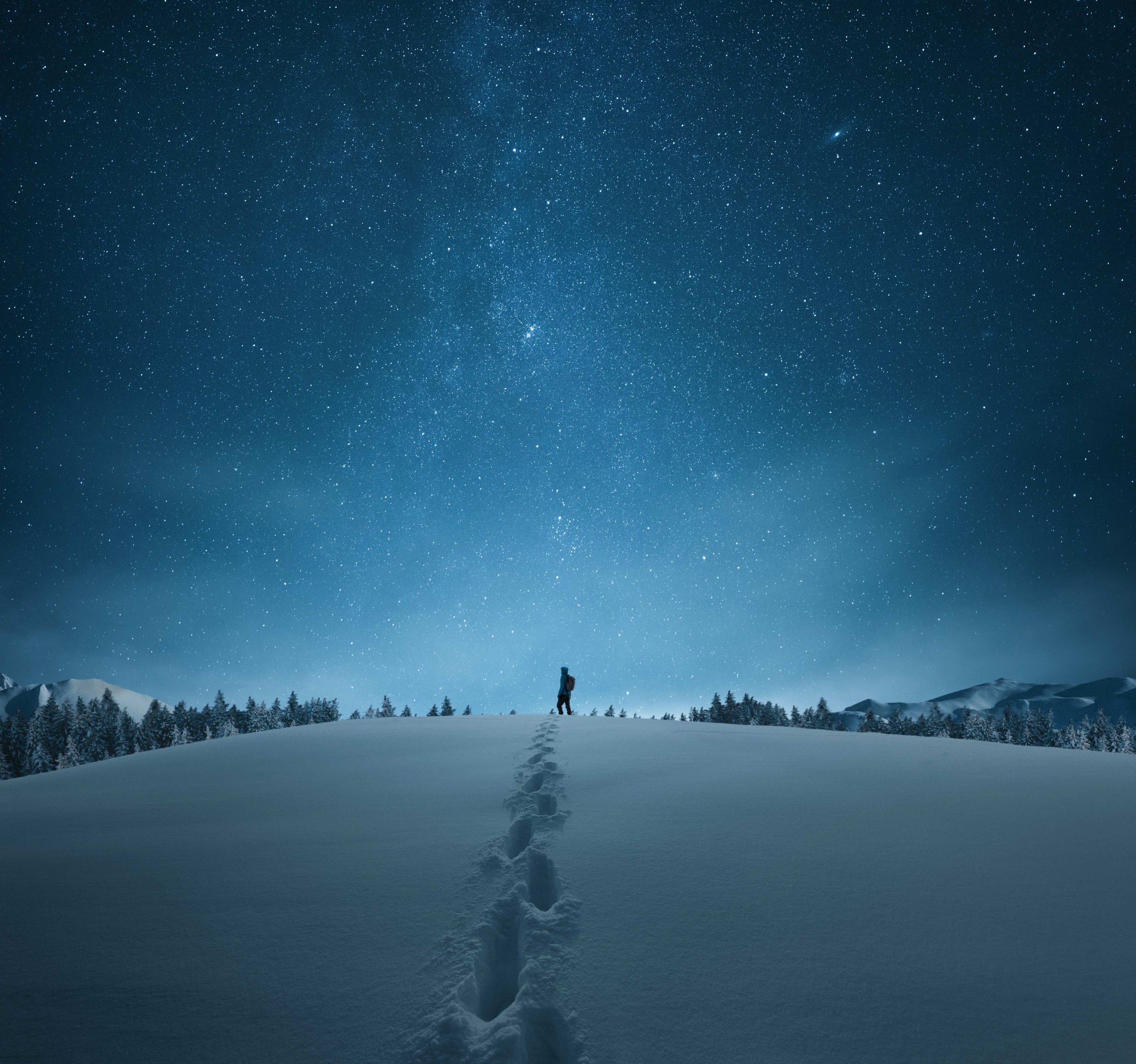 man knee deep in snow under a starry night sky