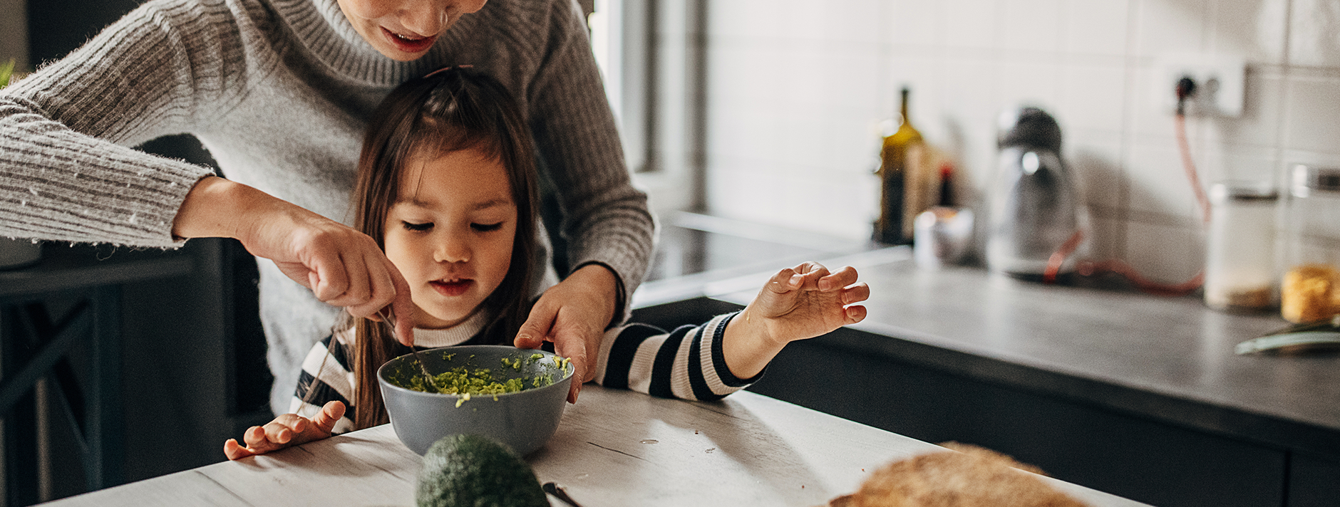 mom helping daughter crush avocados