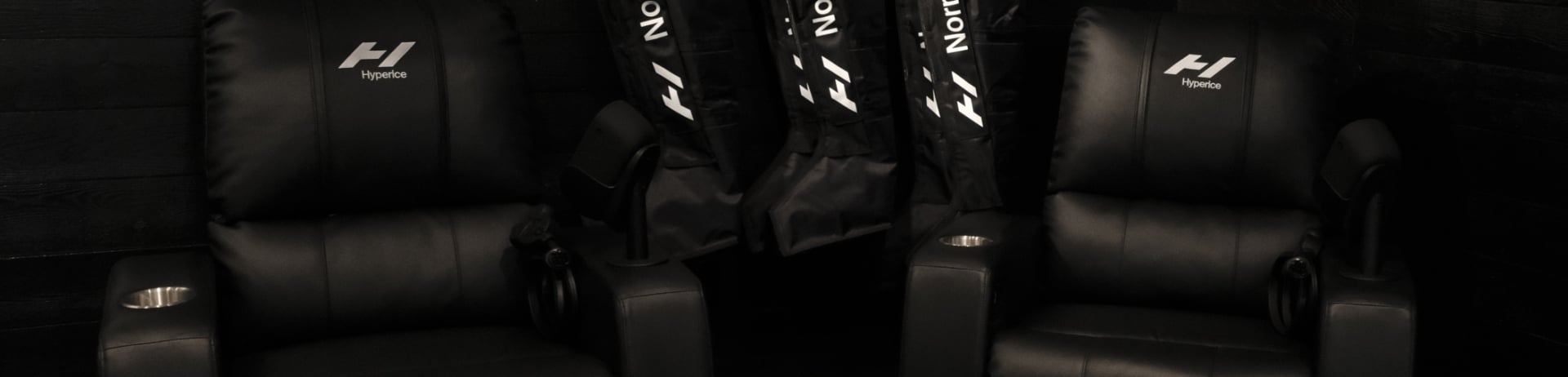 two hyperice recovery chairs in the recovery lounge located at the Fairmont Chateau Whistler with equipment hanging on the wall for guests to use.