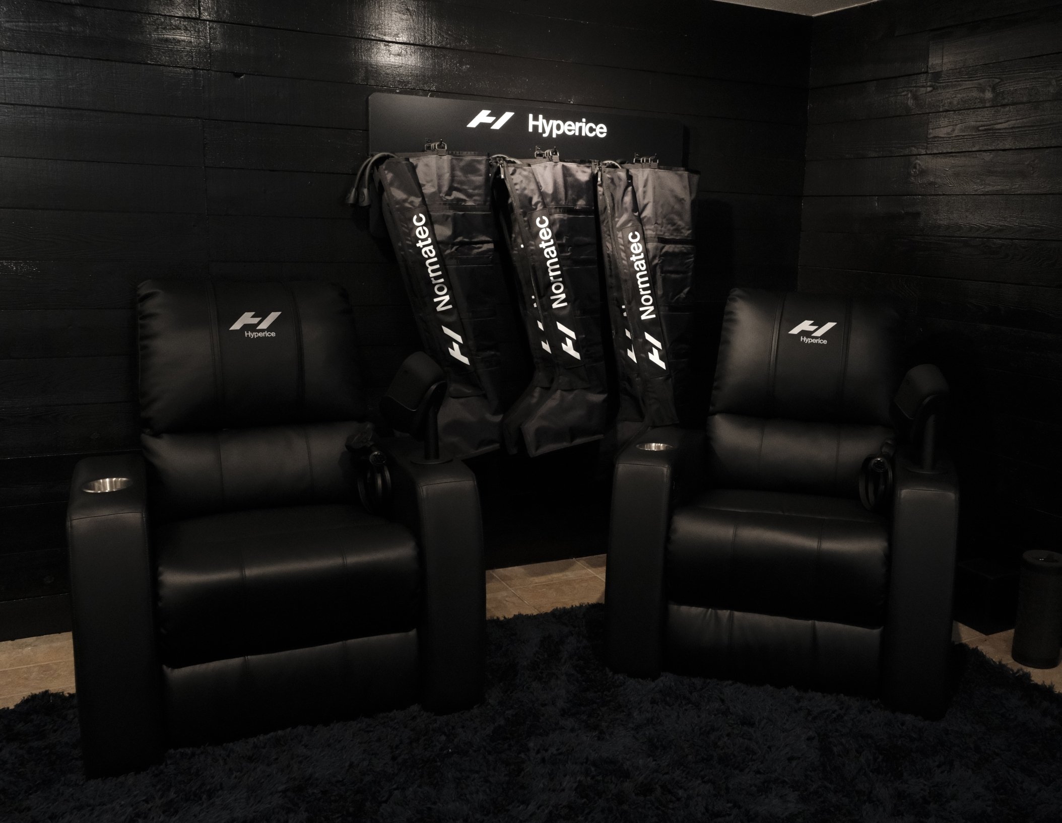 two hyperice recovery chairs in the recovery lounge located at the Fairmont Chateau Whistler with equipment hanging on the wall for guests to use.