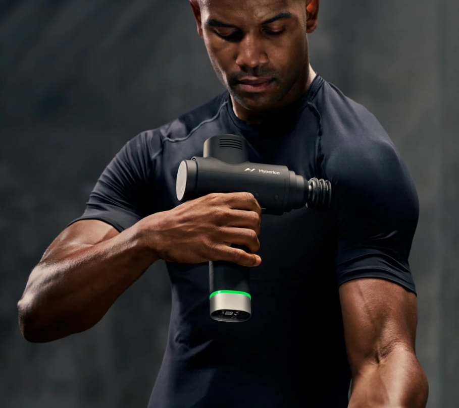 man using the hyperice massage gun to his shoulder to release tension and recovery pre or post workout