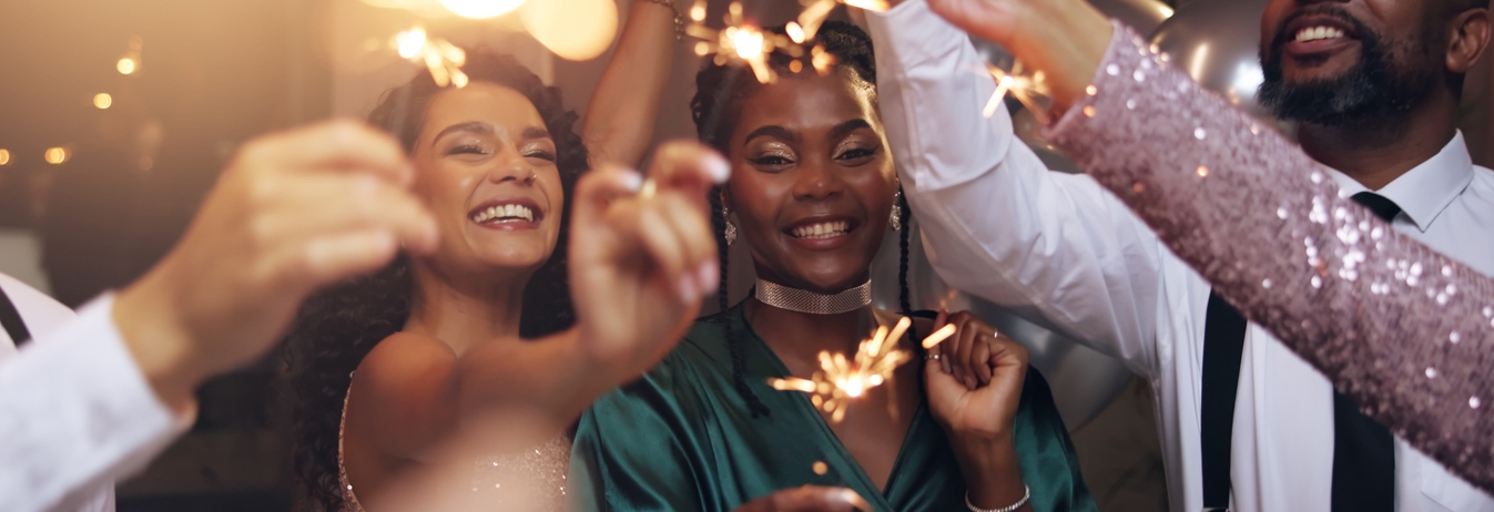 Business people, party and sparklers at night for celebration, diversity and happy for new year countdown. Women, men and smile for friends with fireworks, connection or cheers in group at gala event